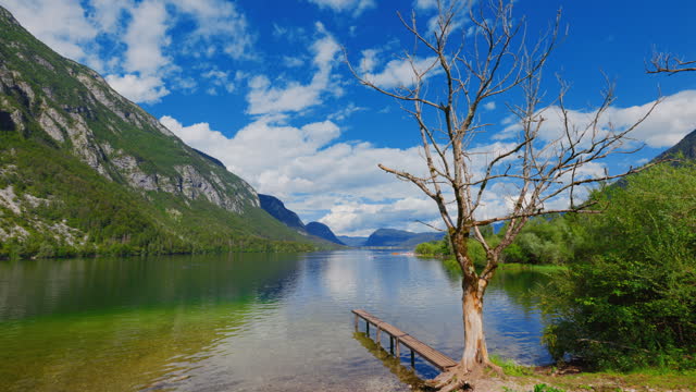 Scenic view of lake Bohinj and mountains against blue cloudy sky
