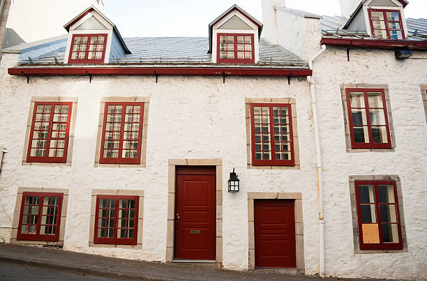 A very old historical stone building on a hill in Old Montreal with red doors and window frames.