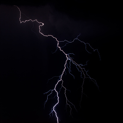 beautiful lightning during a thunderstorm at night in a forest that caused a fire, against a dark sky with rain