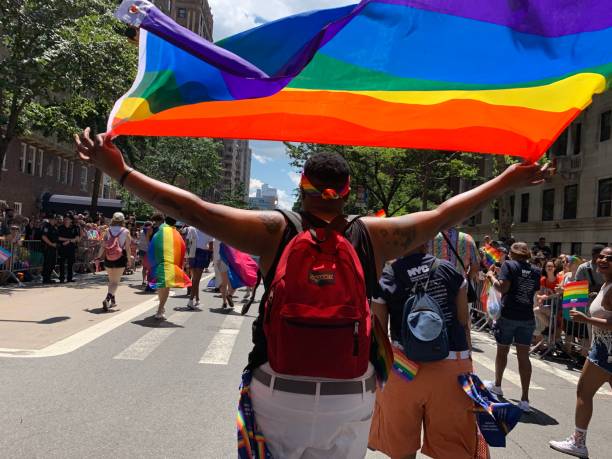 orgulhosamente agitando a bandeira do orgulho - flag gay man american culture rainbow - fotografias e filmes do acervo