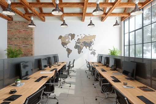 Modern Open Plan Office Interior With Office Chairs, Computers, Plants And World Map Wall Decoration
