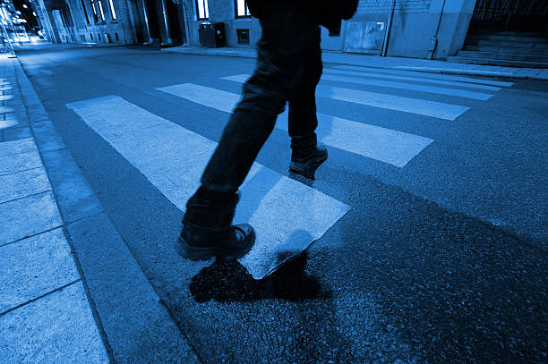 Silhouettes of people legs walking on city street at evening time. Long shadows in golden evening sun. City life.