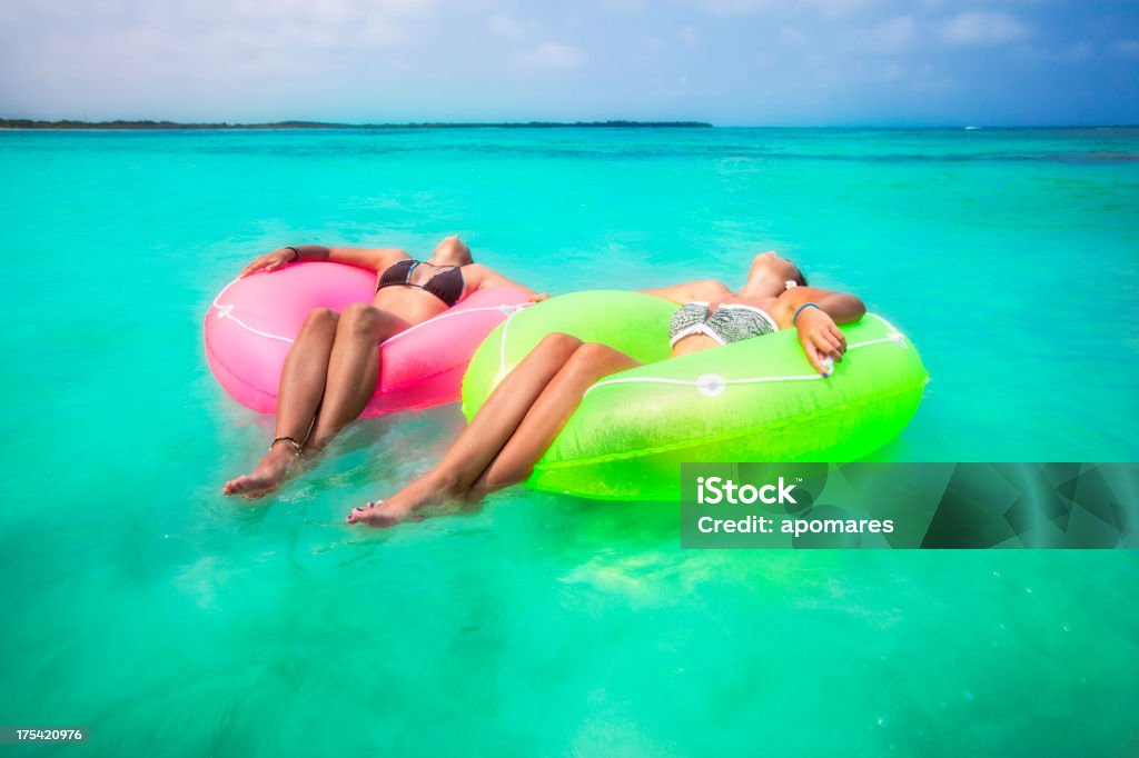 Due giovani donne rilassante con le provette in una spiaggia tropicale - Foto stock royalty-free di Estate