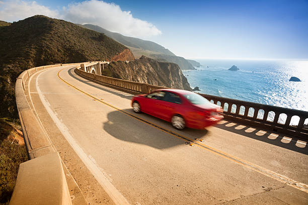 Red car zooms down Bixby Bridge in Big Sur "Bixby Bridge on highway 1 near the rocky Big Sur coastline of the Pacific Ocean California, USA" Bixby Creek stock pictures, royalty-free photos & images