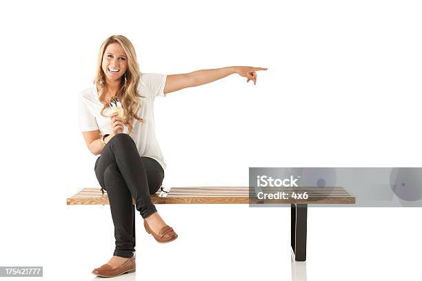 Happy Woman Eating An Ice Cream And Pointing Stock Photo - Download Image Now - Bench, Blond Hair, One Woman Only