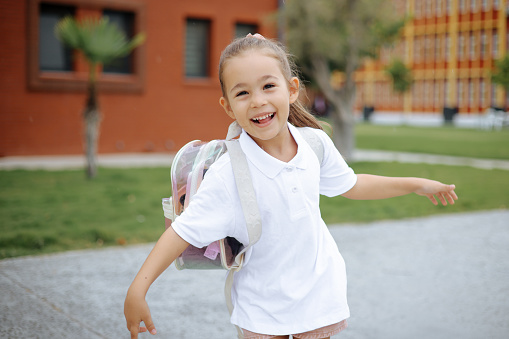 Cute child girl with backpack running and going to school