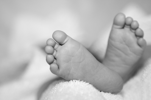 Feet of a newborn baby in a cradle close-up.