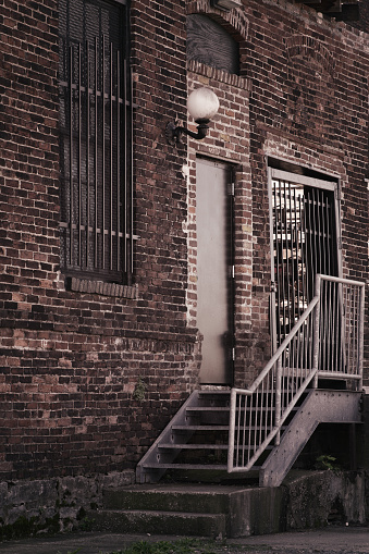 A murky back entrance staircase on an ancient factory building in Nashville, Tennessee, USA. More than a century of haphazard renovation and reconstruction has given this building a comically abstract array of different brick shapes and sizes - truly befuddled 