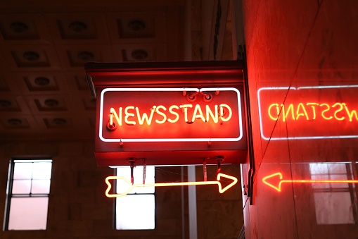 Portland, United States – November 11, 2022: A glowing yellow sign featuring the words 'Newsstande', 'Chatsweld' and 'Directions'