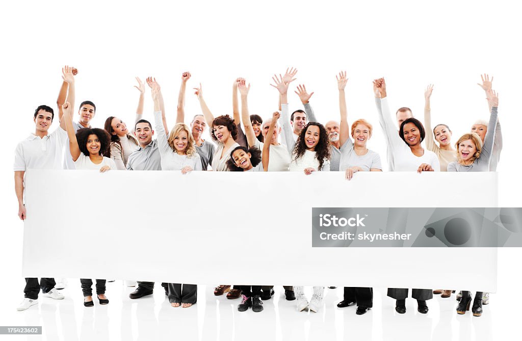 Large group of happy people holding a white board. Large group of a cheerful people with raised hands are holding a big paper for commercials. They are isolated on white background. Holding Stock Photo