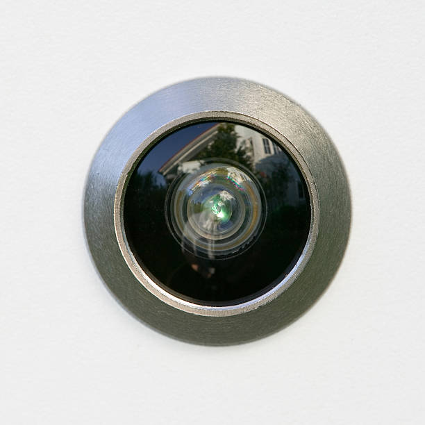 Closeup of a chrome peephole on white background/door