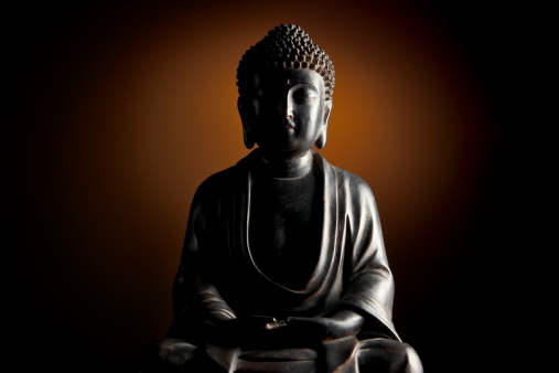 A view of a Japanese Buddha statue.  Eyes closed and face serene.