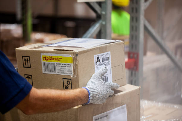 istock Unidentified person's hands carrying cardboard box insode warehouse facility 1754245303