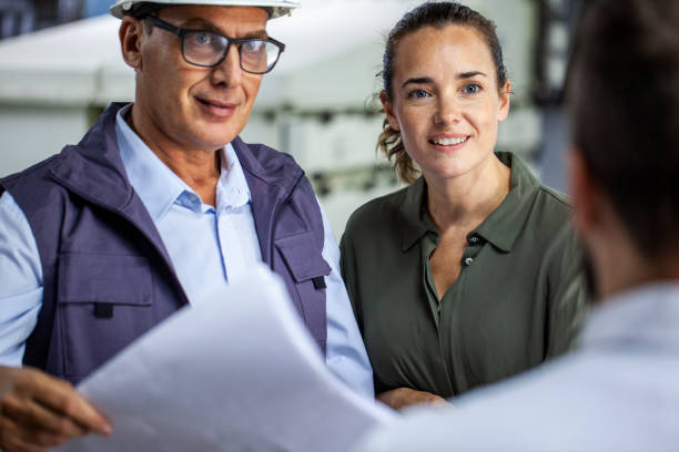 istock Warehouse manager discussing business issues with female manager while looking at blueprints 1754248585