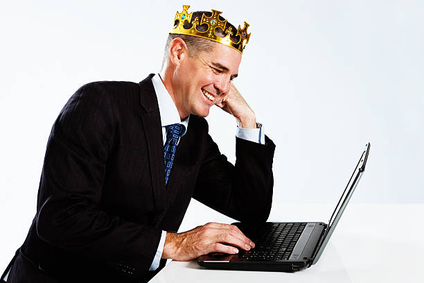 uśmiechająca się biznesmen w royal crown wygląda w laptopie - re2012019 zdjęcia i obrazy z banku zdjęć