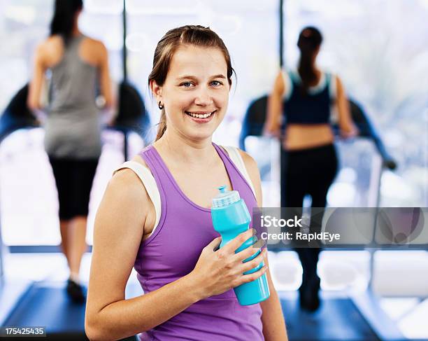 Pretty Woman Smiling With Satisfaction Rehydrates After Exercising In Gym Stock Photo - Download Image Now