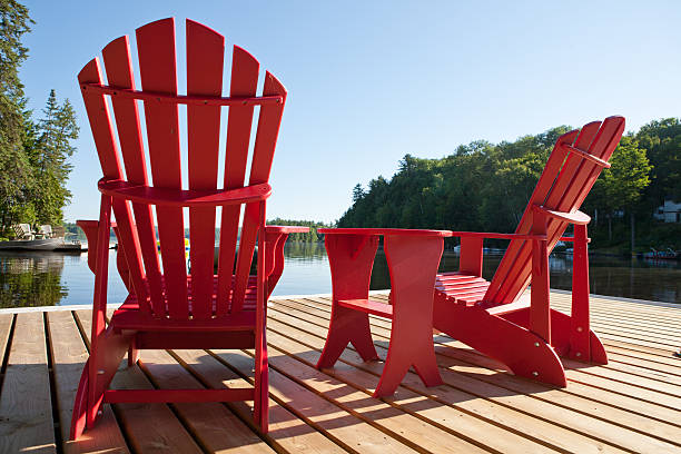 Muskoka Chairs on a Sunny Morning Muskoka chairs with a view of the lake. cottage life stock pictures, royalty-free photos & images