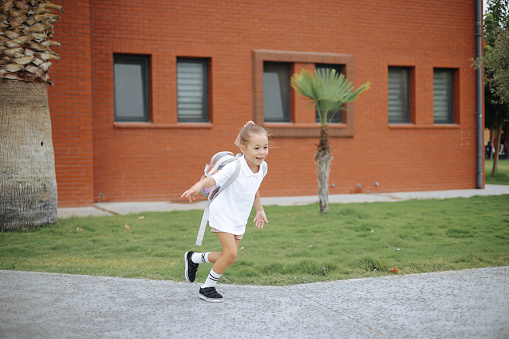 Cute child girl with backpack running and going to school