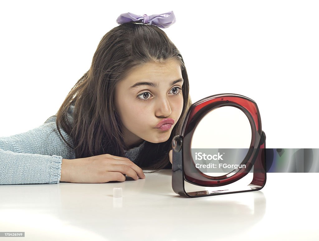 Teenage girl looking at mirror A beautiful teenage girl looking to small mirror Girls Stock Photo