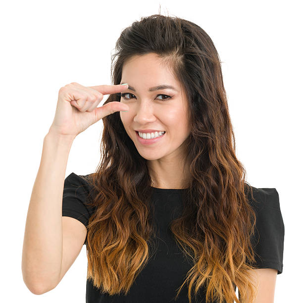 Young Woman Teeny Tiny Finger Gesture Portrait of a young woman on a white background. http://s3.amazonaws.com/drbimages/m/an.jpg short story stock pictures, royalty-free photos & images