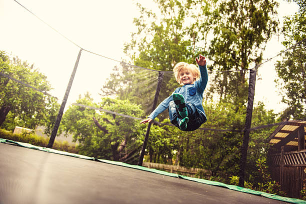 niño saltar en un trampolín - trampolín artículos deportivos fotografías e imágenes de stock