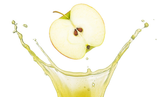 Half organic apple falling into crown shape juice splash isolated on white. Real studio shot photography.