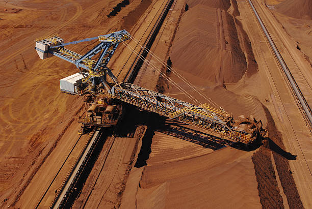 Ore reclaimer collecting crushed ore on a minesite. An aerial view of a reclaimer used to harvest crushed iron ore stockpiles on a mine site. Reclaimer stock pictures, royalty-free photos & images