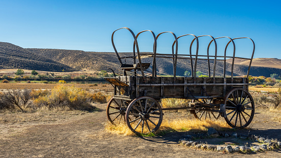 A pioneer wagon sits above Three Island Crossing with the Oregon Trail in the background