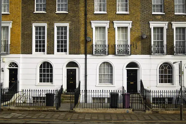 Facades of London rowhouses, typical structured with small fences in front, some steps at entrence, brick facade.