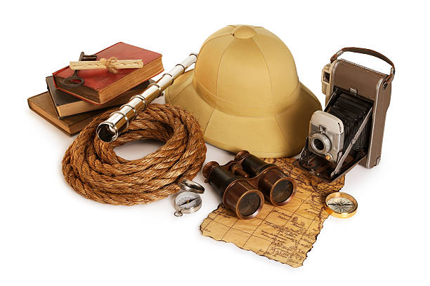 This is a photo of a pith helmet,binoculars,periscope,compasses,map,old rope,books and camera isolated on a white background.