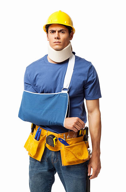 Injured Construction worker - Isolated Portrait of an injured construction worker wearing tool belt. Vertical shot. Isolated on white. man with arm sling stock pictures, royalty-free photos & images