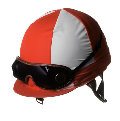 A red and white racing helmet with goggles worn by horse racing jockeys isolated on a white background.