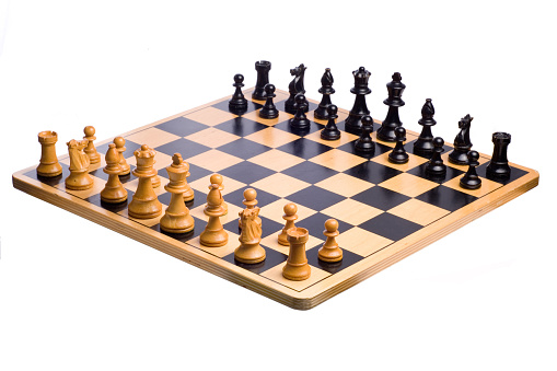 A wooden chessboard set up prior to play