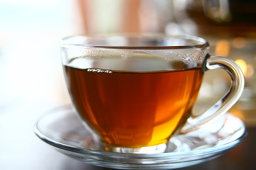 Cup of tea with old book and spectacles on an old polished wooden surface