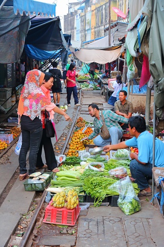 Vendors sell food at Mae Klong railway tracks market in Thailand. The market is notable for its location on active railroad line.