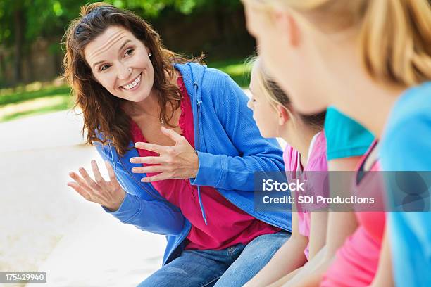 Woman Mentoring Group Of Girls At A Park Stock Photo - Download Image Now - Adolescence, Group Of People, Instructor