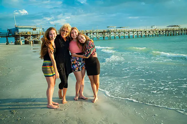 "Happy Grandmother with her three real lovely grandaughters at sunset at the beach. Pier in the background. This was taken in the Clearwater area, Florida."