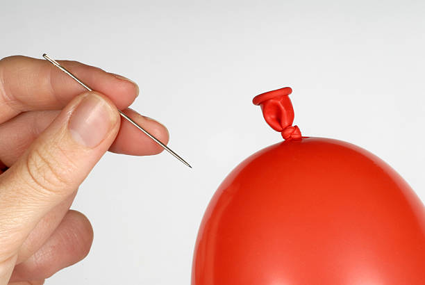 istock Hand holding a needle about to pop a red balloon 175429986