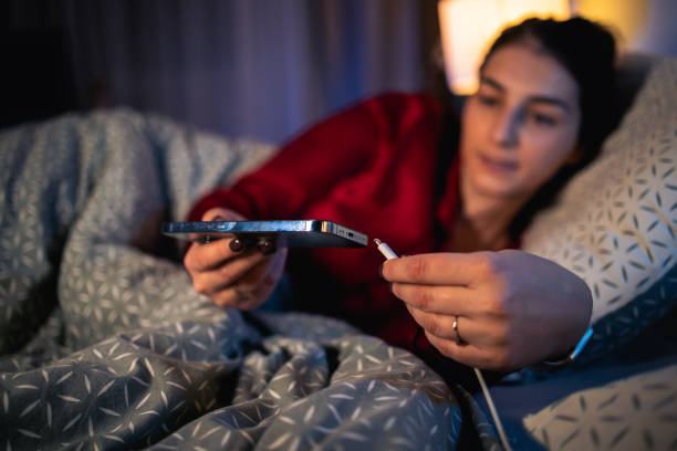 Woman putting smartphone on a charger before sleeping