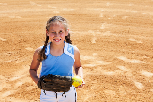 Girl (9 years) playing softball, standing on pitcher's mound.