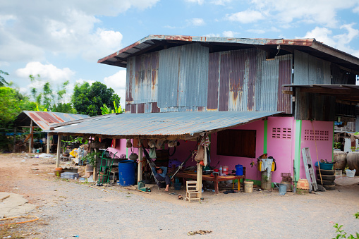 Simple pink colored weathered   thai farm house with iron sheets on upper floor  in rural village Parangmee near Noen Maprang  in province Phitsanulok