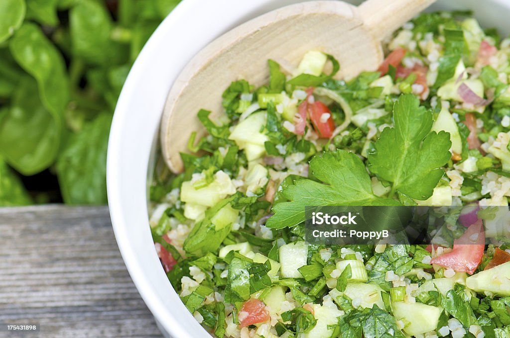 White Bowl of Tabbouleh from Above "White bowl of homemade tabbouleh served in the garden with wooden spoon, shot from above." Couscous Stock Photo