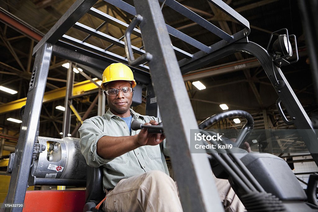 Afroamericana trabajador conducir una carretilla elevadora - Foto de stock de Carretilla elevadora libre de derechos