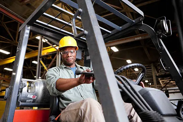 Photo of African American worker driving forklift