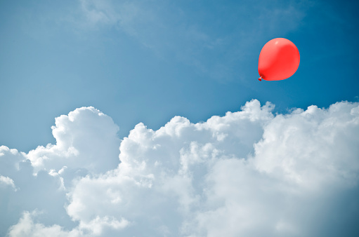 red baloon between impressive cloud formation