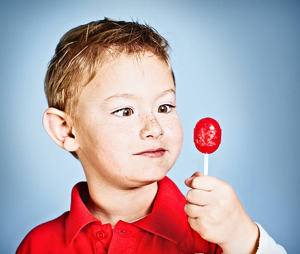 close up studio portrait of blonde 4 year old baby boy in white t-shirt on orange background