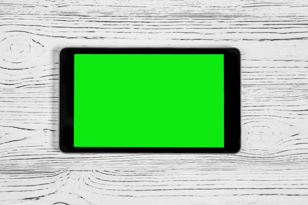 istock Black tablet with green screen on a wooden table mock up. Copy space chroma key display. 1754341350