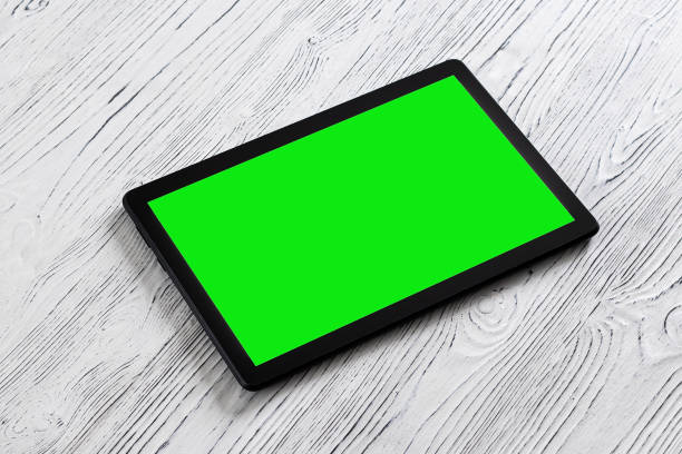istock Black tablet with green screen on a wooden table mock up. Copy space chroma key display. 1754341371