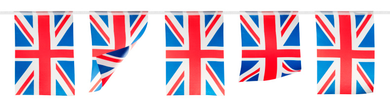 A row of red white and blue, union jack bunting. Each flag is rectangular and hanging from a white ribbon. A couple of them are are blowing in a light breeze. They are in a line and isolated on a white background with a clipping path.