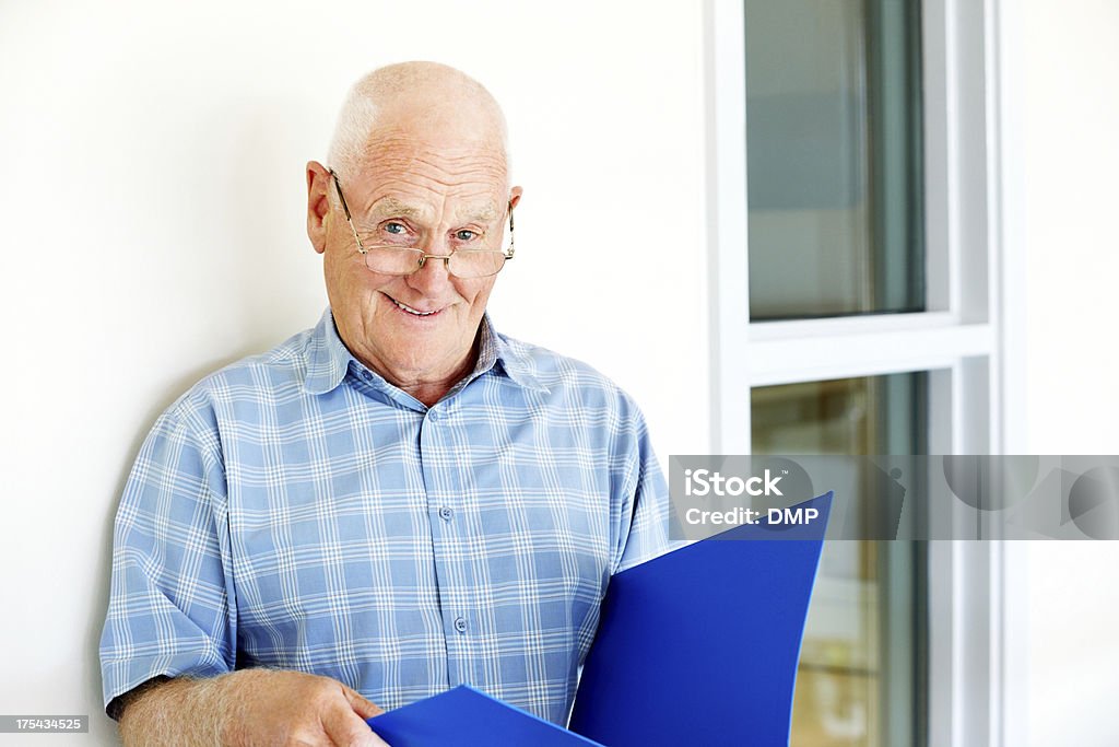 Senior hombre que agarra un archivo y mirando a la cámara - Foto de stock de 70-79 años libre de derechos